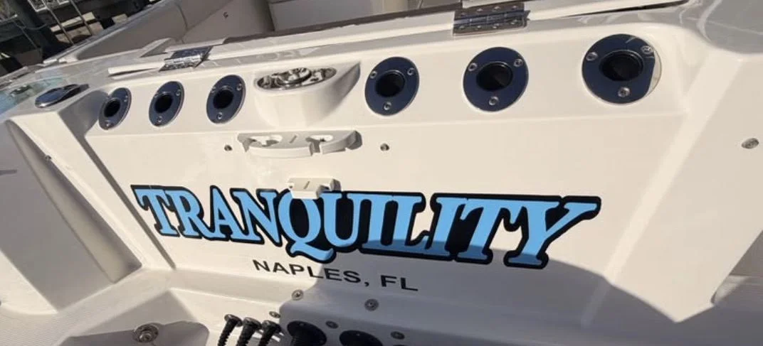 Boat named Tranquility, Naples FL, in blue vinyl lettering with black outline